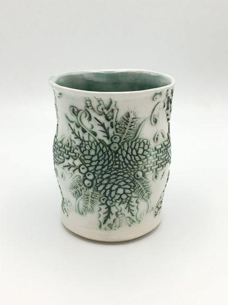 White porcelain tumbler with green Christmas-inspired carvings