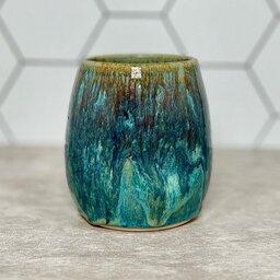 A ceramic tumbler coated with a glossy turquoise glaze, giving it a smooth and shiny finish