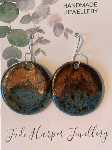 Handmade round ceramic earrings with a blue and copper glazes, creating a unique and vibrant design